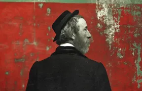 Bearded 19th-century man in bowler hat before weathered red wall