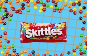 Original Skittles bag surrounded by scattered rainbow Skittles candies