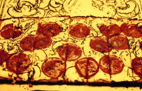 Rectangular pepperoni pizza close-up over a sepia vintage newspaper background