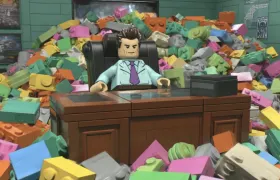 LEGO minifigure businessman at a desk buried in giant bricks