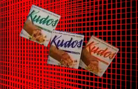 Three vintage Kudos granola bar boxes on a red grid background