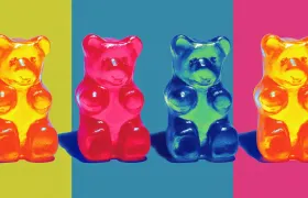 Four glossy gummy bears in orange, red, blue and yellow