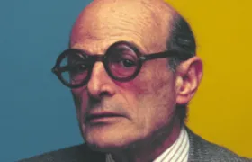 Portrait of an older man in round glasses and grey suit