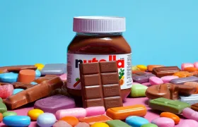 Nutella jar surrounded by chocolate bars and colorful candies