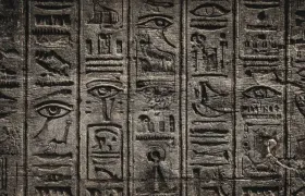 Egyptian hieroglyphs carved in dark stone with wedjat eyes and ankh